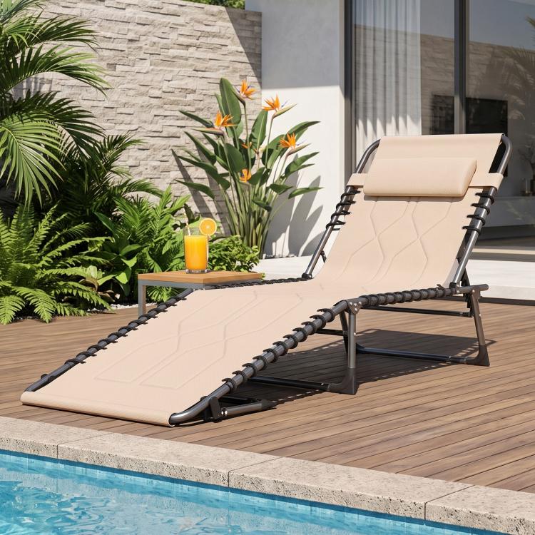 Beige padded folding chaise lounge chair with headrest on outdoor deck by pool