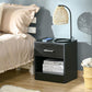 Black wood-grain side table with silver drawer handle and open storage shelf.