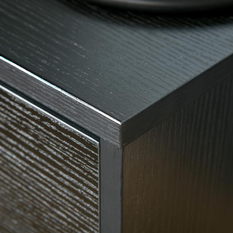 Close-up of black wood-grain tabletop edge and side panel detail.