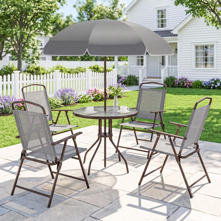 Outdoor gray patio dining set with umbrella over round glass table and four folding chairs