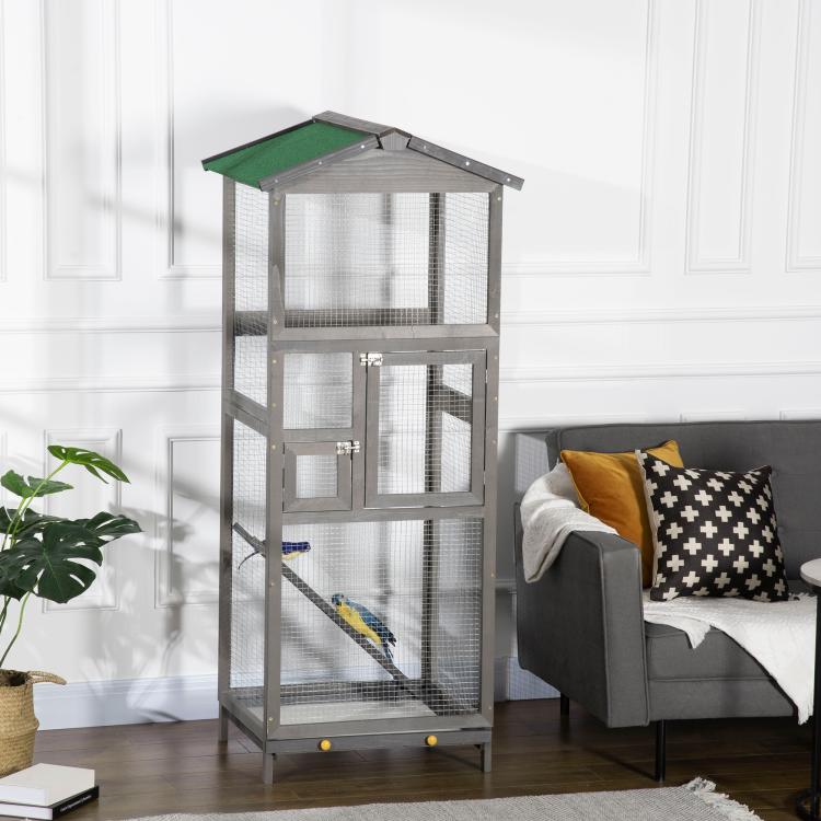 Grey outdoor bird cage aviary house with green roof, wire doors, and perch inside