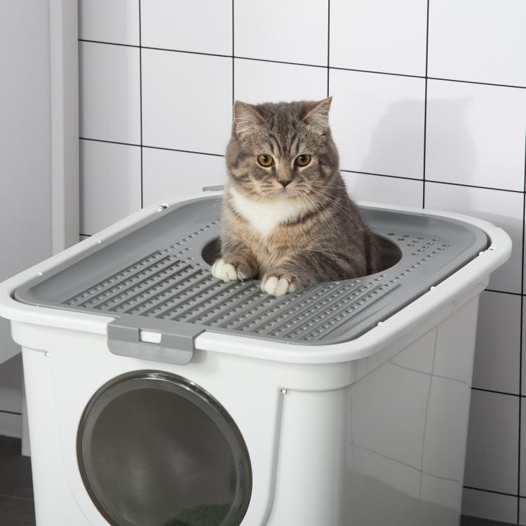White covered cat litter box with round front door and gray tabby cat on top tray
