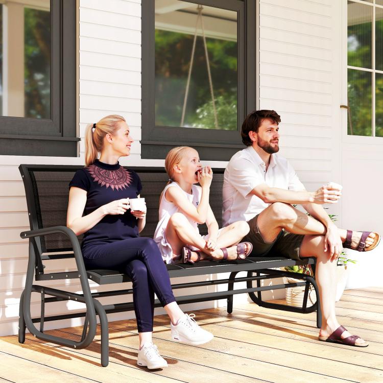 Outdoor glider bench with dark mesh back and black metal frame on wooden deck