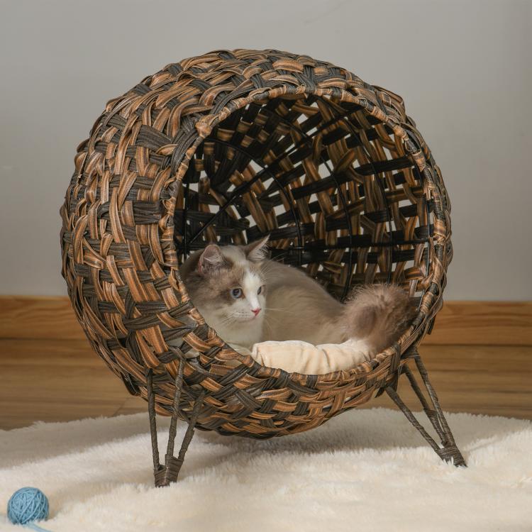 Brown woven cat condo with cream cushion and raised legs, cat resting inside