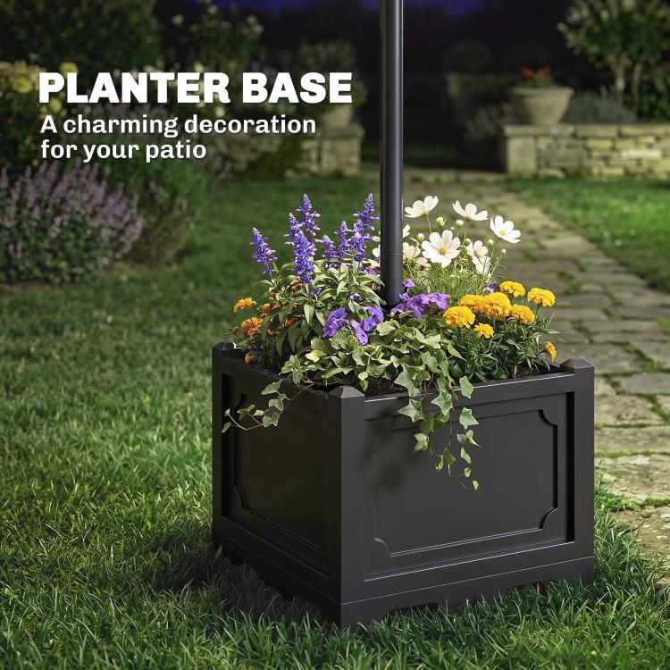 Square planter base with dark finish holding flowers next to solar lamp post light