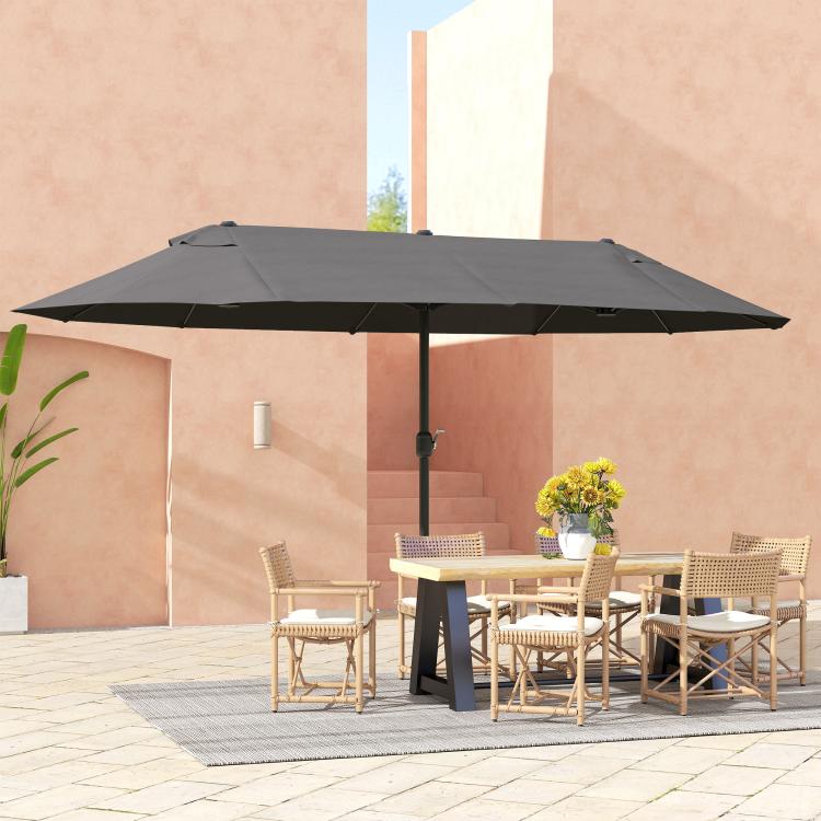 Gray patio umbrella with closed crank handle and wide canopy over patio furniture