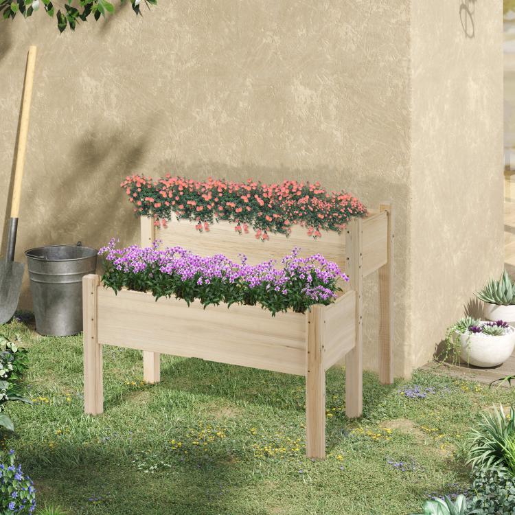 Two-tier raised wooden planter bed with pink flowering plants in yard