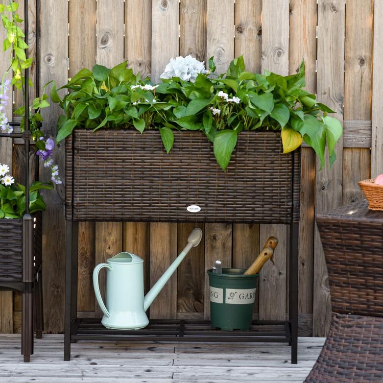 Brown rattan-style wicker planter box with black legs and lower storage shelf