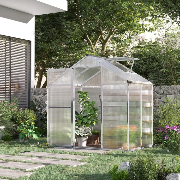 Walk-in polycarbonate greenhouse in garden with clear walls and roof vent