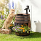 Rustic wooden barrel water fountain with black pump spraying water, planted with colorful flowers