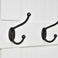 Cream hall tree with black coat hooks and curved mounting brackets