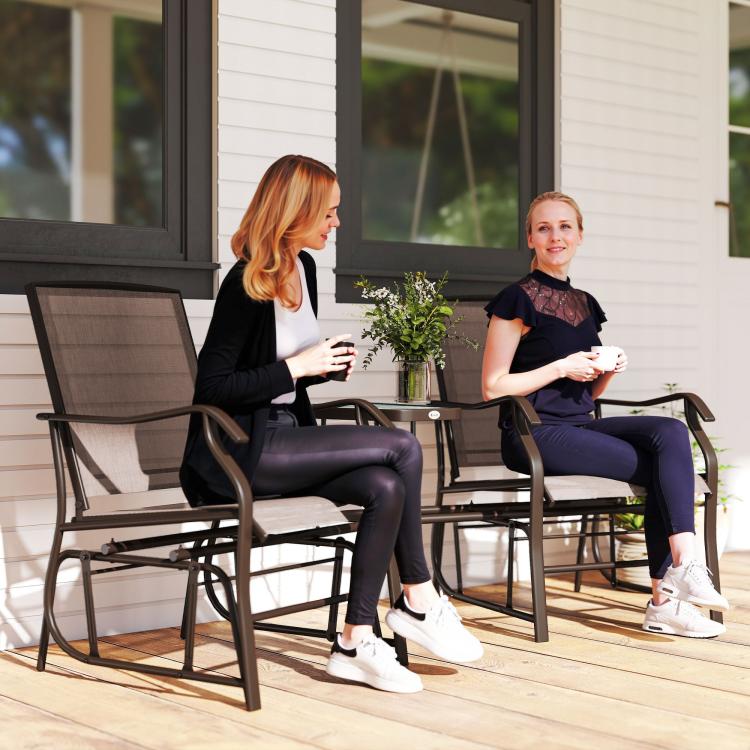 Two patio rocking chairs with brown sling backs and seats beside a small coffee table