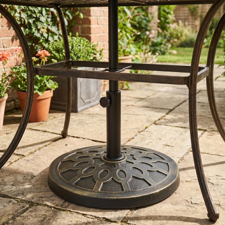 Black round resin umbrella base with ornate pattern and central pole socket