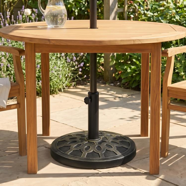 Black round resin umbrella base stand centered under a patio table