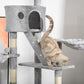 Gray cat climbing tower with condos, rope scratching post, and perches; cat in lower house