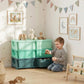 Green 3-tier kids storage organizer with open drawers beside a child