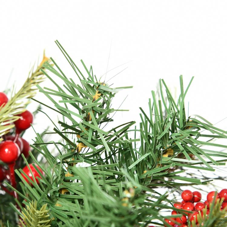 Close-up of pre-lit artificial Christmas tree with green needles and red berries