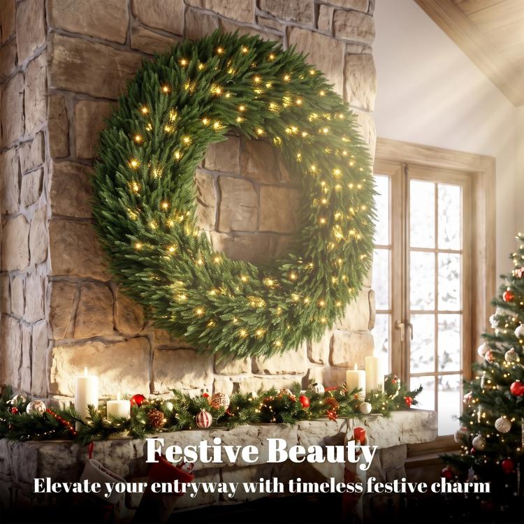 Green artificial wreath with warm white LED lights, mounted on stone wall