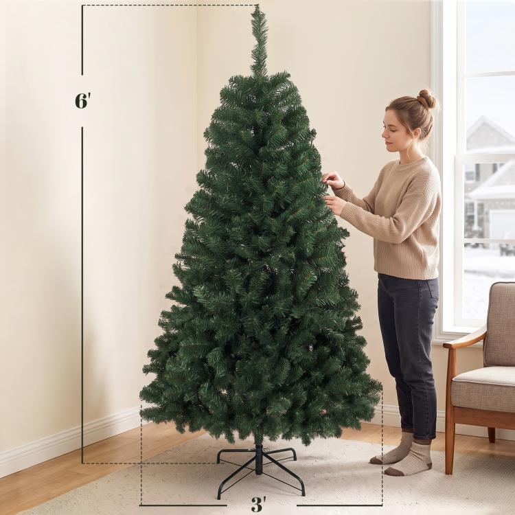 Artificial green Christmas tree with dense branches, side view on metal stand