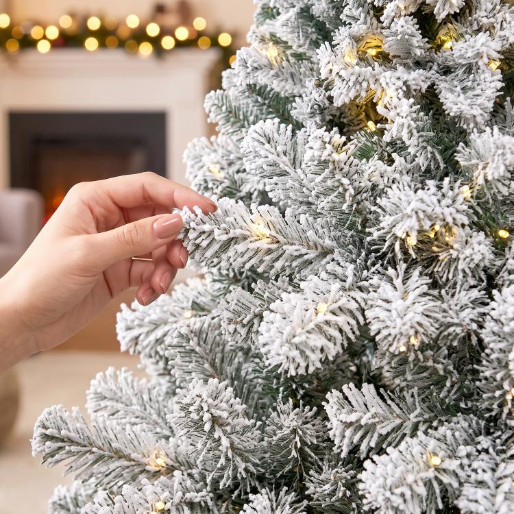 Flocked Christmas tree branches with warm white lights and hand shown adjusting tips