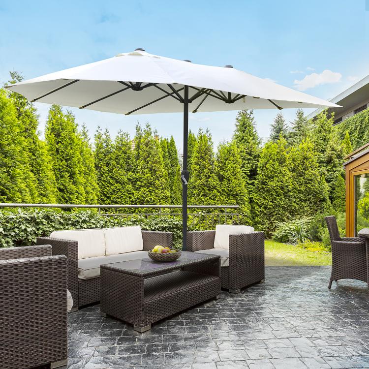 Beige patio umbrella open over outdoor seating, central dark pole and weighted base