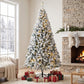 Snow-flocked prelit Christmas tree with full silhouette and warm lights, standing on base.