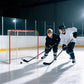 Hockey goal with red frame and white mesh net, players aiming nearby