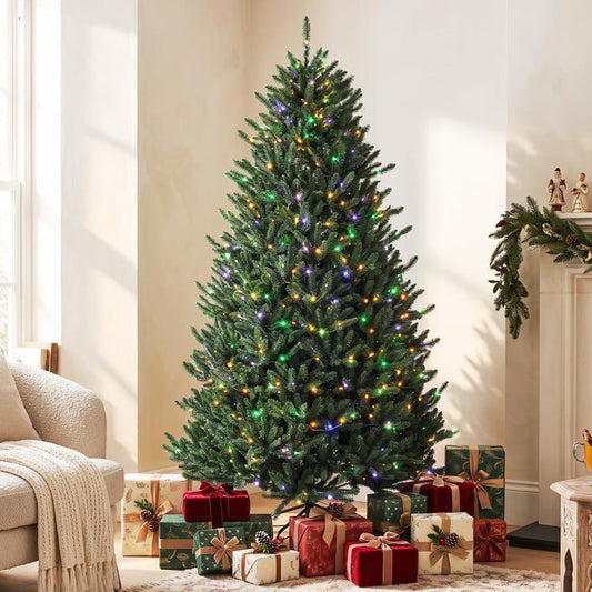 Prelit Colorado blue spruce Christmas tree with multicolored lights and wrapped gifts at base