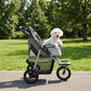 Light gray dog stroller with mesh sides and canopy, small dog inside, 4-wheel frame