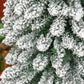 Snow-flocked slim artificial Christmas tree with dense green needles