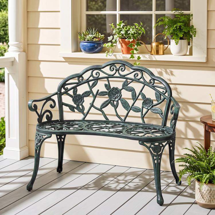 Green cast aluminum bench with ornate rose-and-leaf backrest and openwork seat