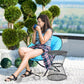 Black hourglass side table with round top, shown outdoors beside a seated person