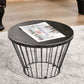 Black metal round-top hourglass side table holding a newspaper on top