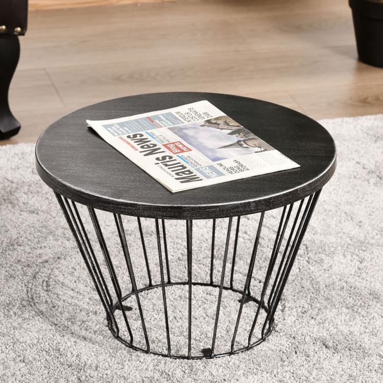 Black metal round-top hourglass side table holding a newspaper on top