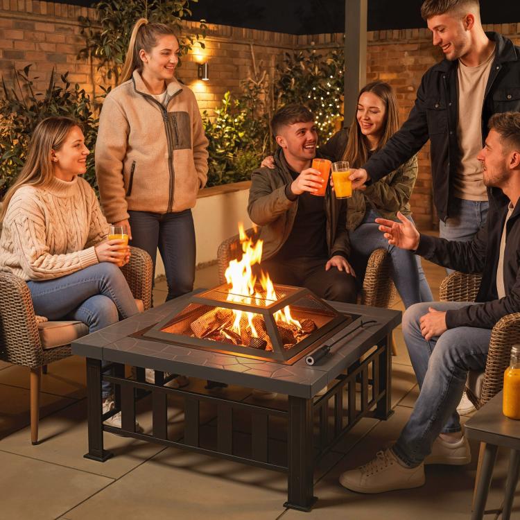 Square steel fire pit with burning logs and mesh spark screen on outdoor patio