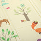 Forest animal play mat with tree print, fold seams on light beige surface