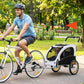 White pet bike trailer hitched to bicycle, dog seated behind mesh front window