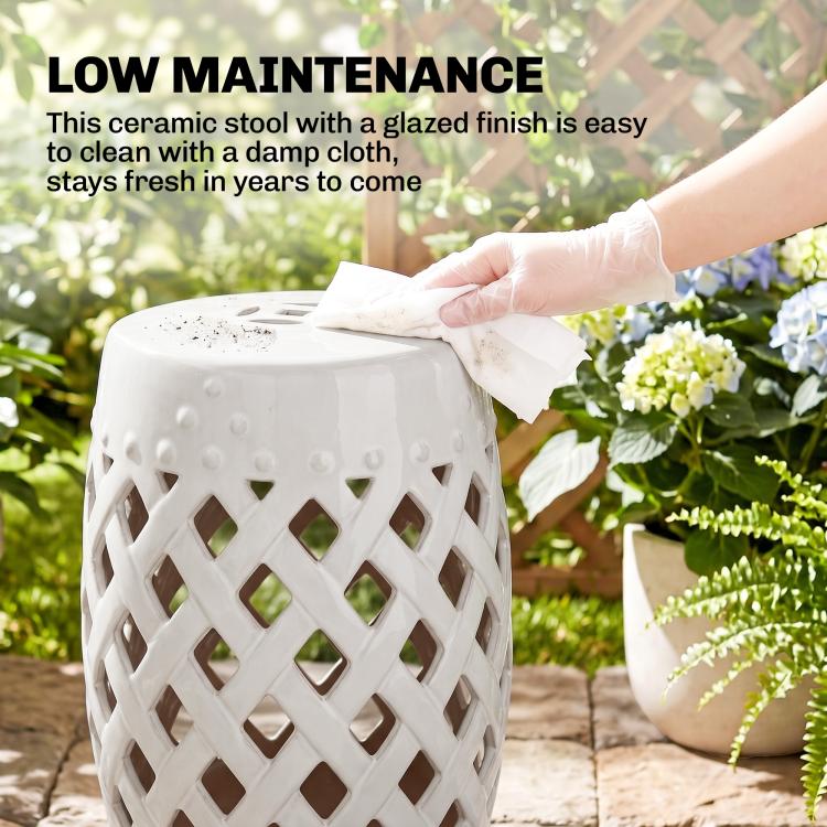 White glazed ceramic garden stool with lattice cutouts being wiped clean, perforated top.