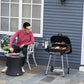 Charcoal barbecue grill with open lid, side shelf, and cooking grate on stand