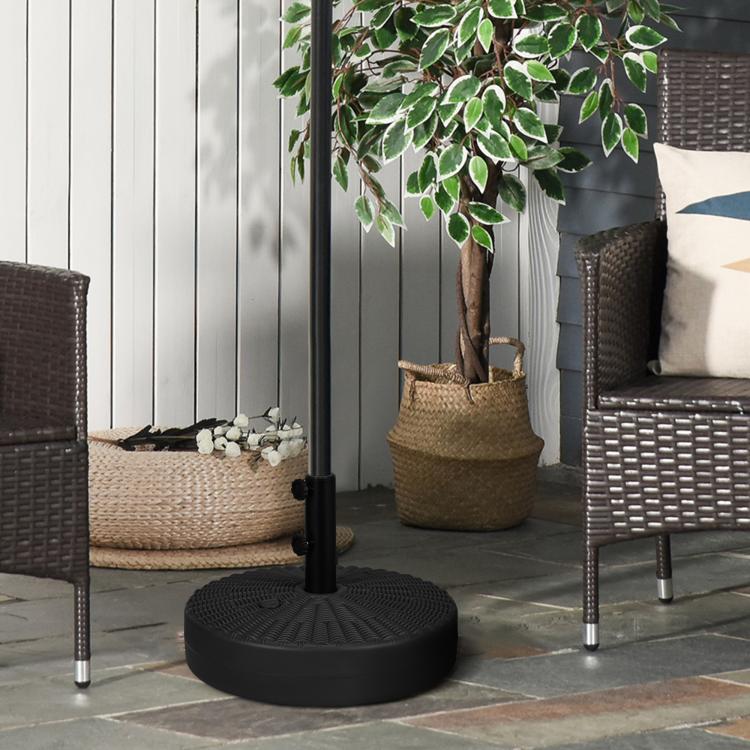 Black umbrella base with vertical pole sleeve and two side knobs, standing outdoors