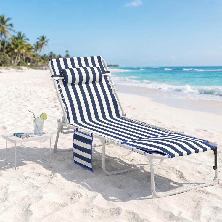 Blue-and-white striped folding tanning chaise lounge chair with side table on sand
