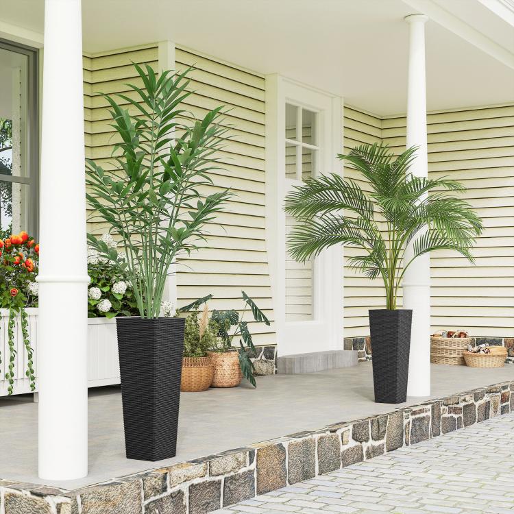 Two black tall woven planters with potted plants on an outdoor patio