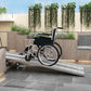 Wheelchair on aluminum ramp at doorway with ribbed non-slip panels and side rails