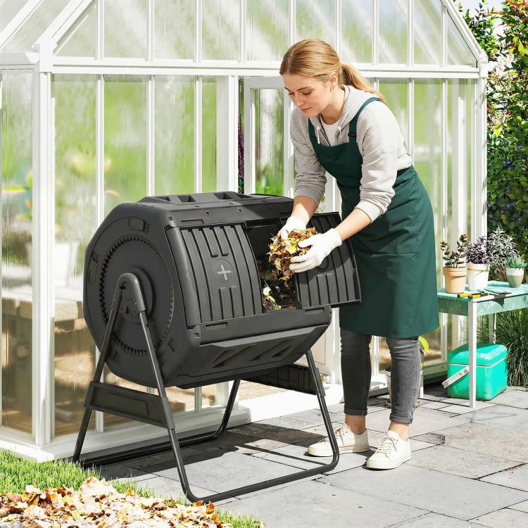 Black outdoor tumbling compost bin with front loading door open while adding compost