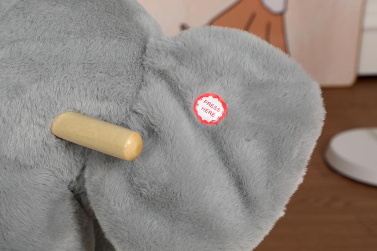 Grey plush elephant toy with wooden safety handle on the rocker seat