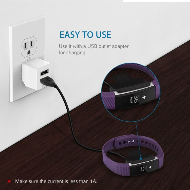 Fitbit Alta charging clip attached to a purple band with USB cable