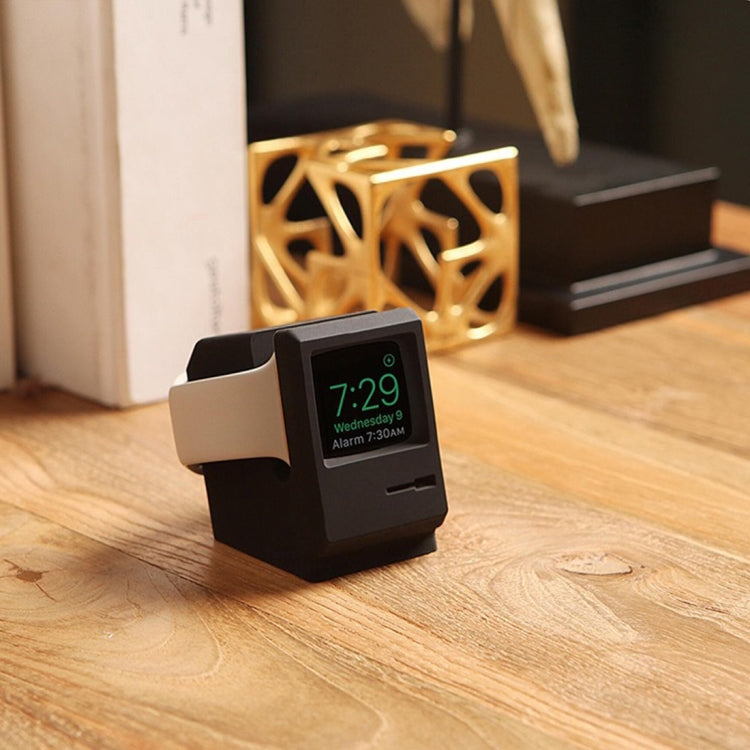 Black Apple Watch charging dock stand on wood surface, front view with time display