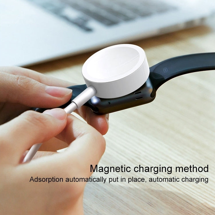 Hand attaching a white magnetic charging puck to a dark smartwatch band