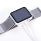 White charging cable end with square puck connected to smartwatch on mesh strap