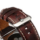 Dark brown leather watch band close-up with metal buckle and stitched strap holes